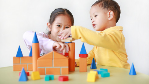 Zwei Kinder bauen mit Holzklötzen Türme.