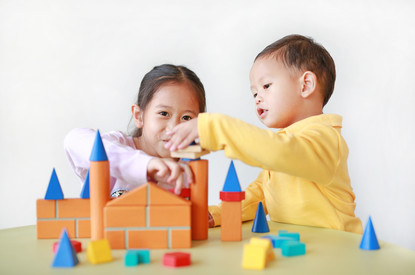 Zwei Kinder bauen mit Holzklötzen Türme.