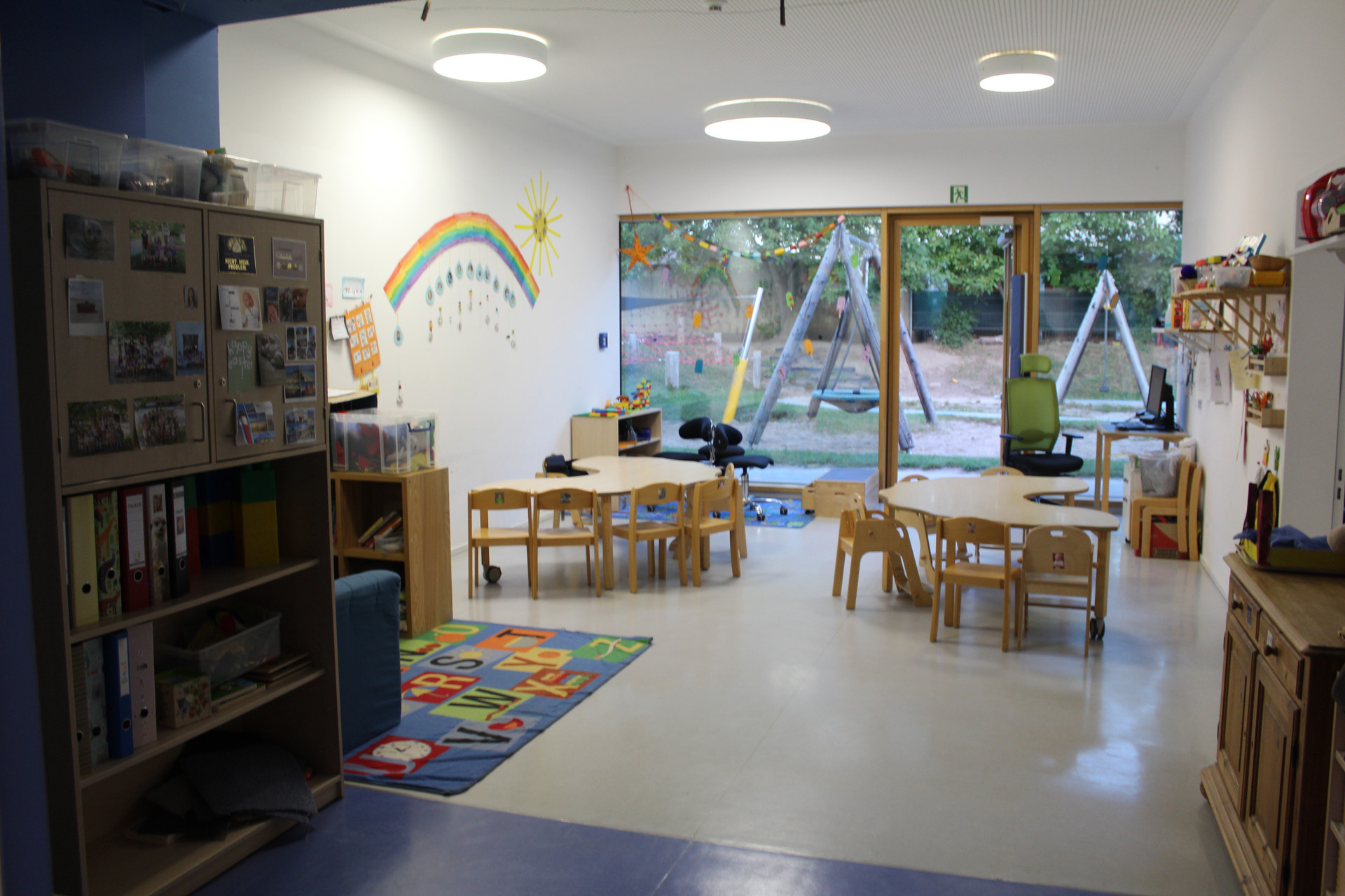 Gruppenraum mit Tischen, Stühlen und Spielmöglichkeiten
