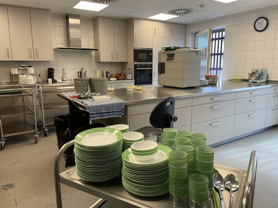 Blick in die Küche. Auf einem Transportwagen ist Geschirr bereitgestellt.